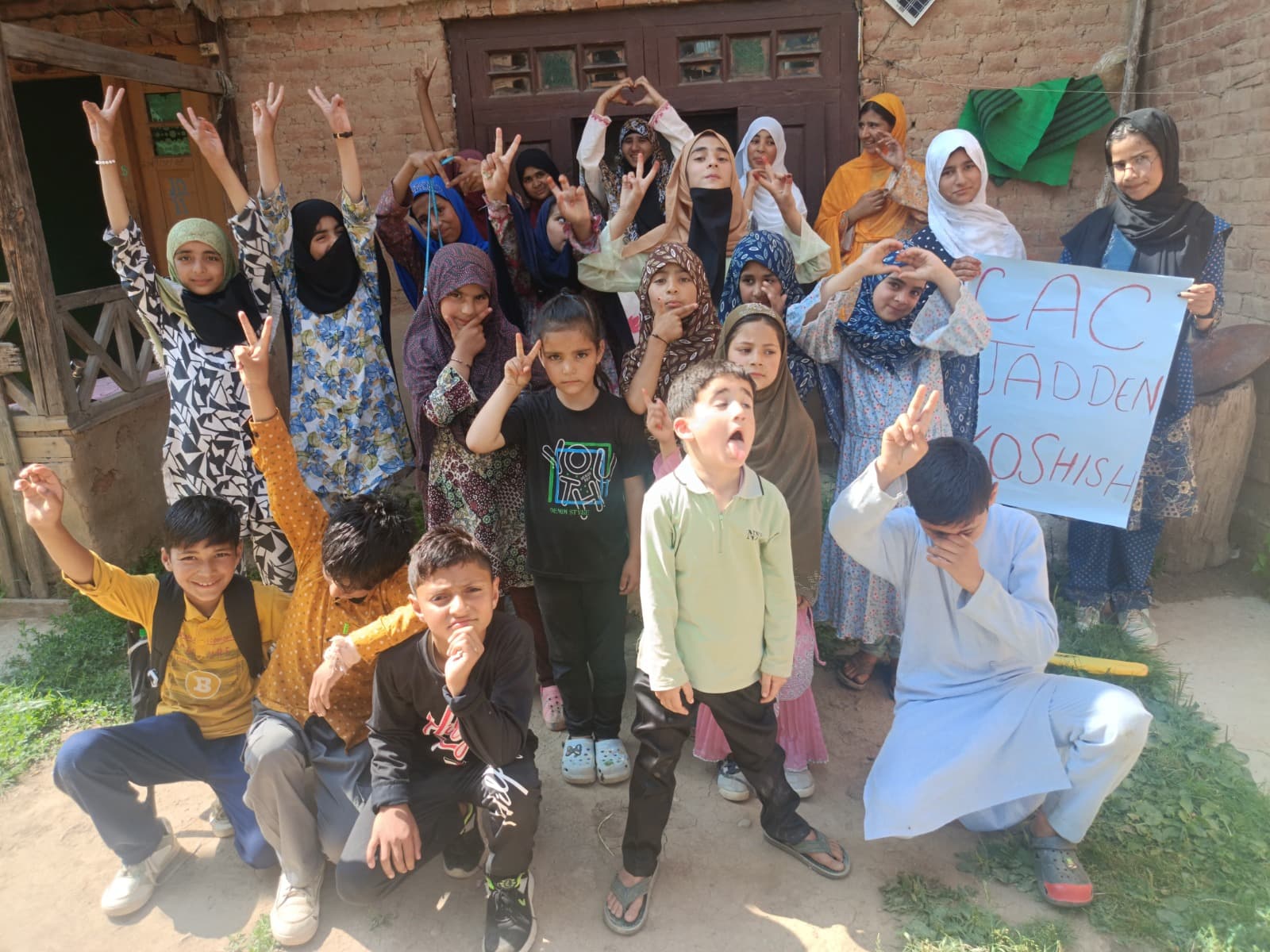 A group of excited children flashing peace signs outside the KOSHISH Community Action Centre in Jadden