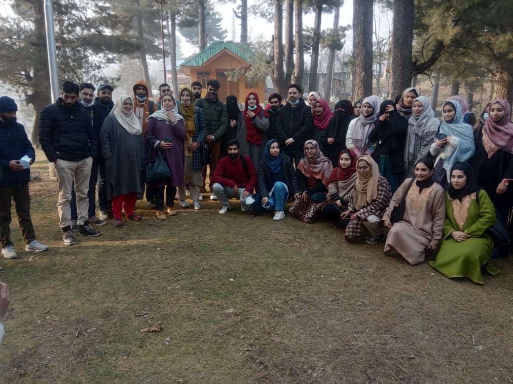 A large group of KOSHISH team members and volunteers posing for a group photo under pine trees in winter