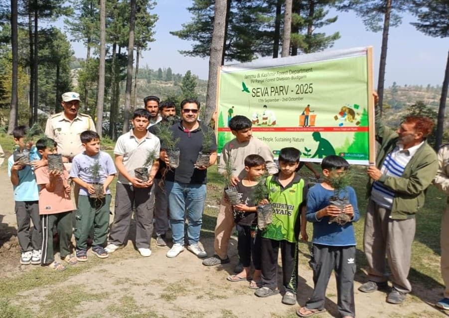Children and officials holding saplings at the J&K Forest Department Seva Parv tree-planting event
