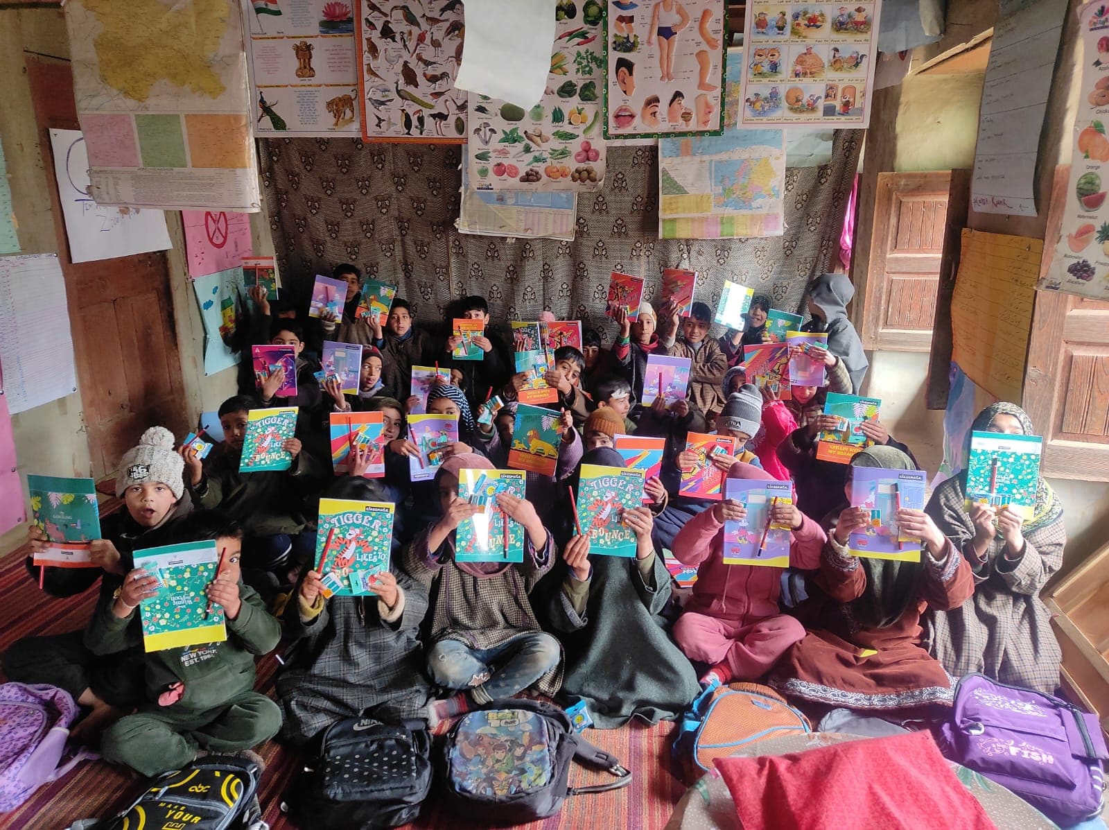 Children in a classroom holding up colourful storybooks distributed by KOSHISH