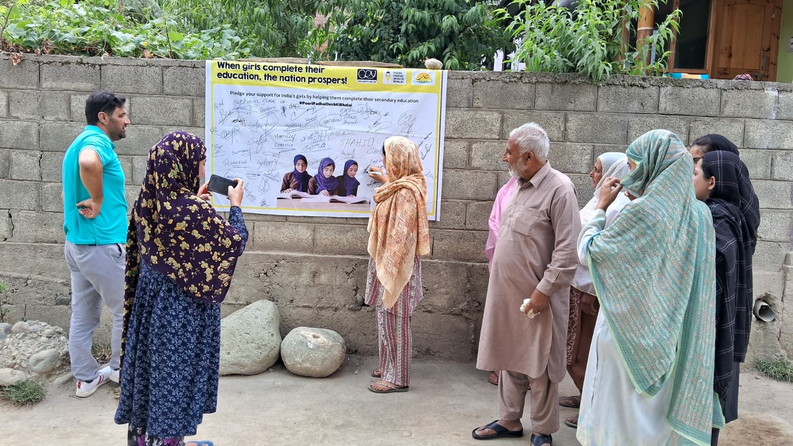 Community members signing the Poori Padhai Desh Ki Bhalai pledge wall supporting girls' secondary education
