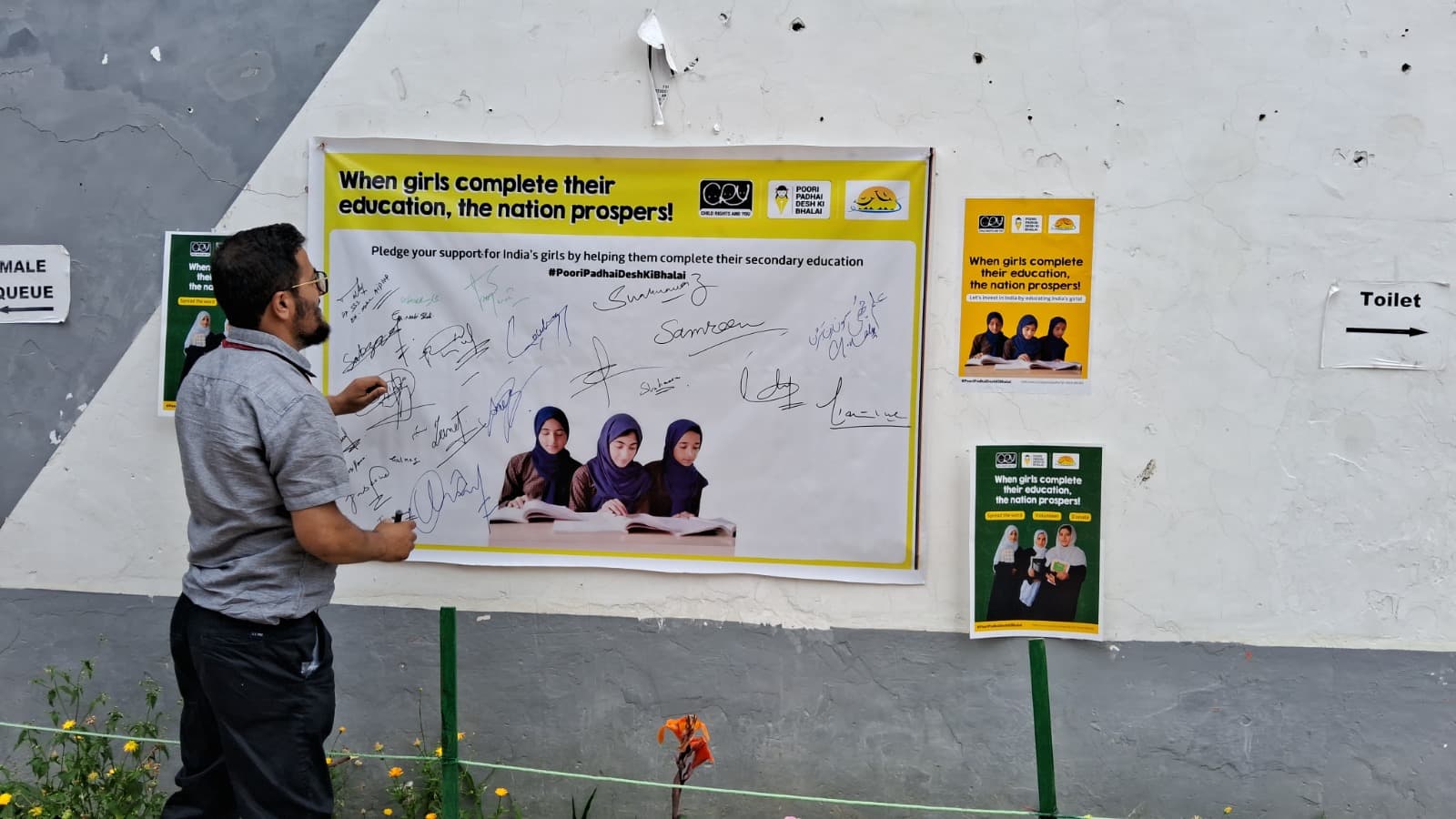 A KOSHISH team member adding his signature to the girls' education pledge wall at a community event